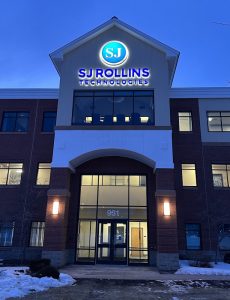Night time photo of the front entrance of the SJ Rollins Technologies building with a face lit and halo lit illuminated channel letters and logo